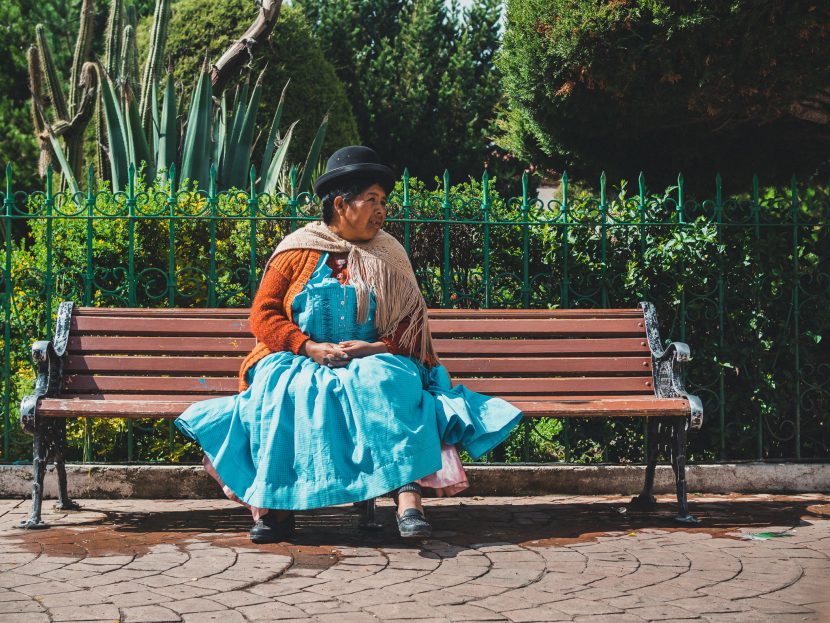 A woman in a blue dress sits on a bench