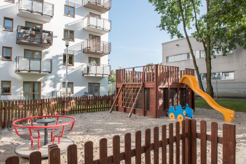 Plac zabaw na podwórku osiedla, drewniana zjeżdżalnia i piaskownica