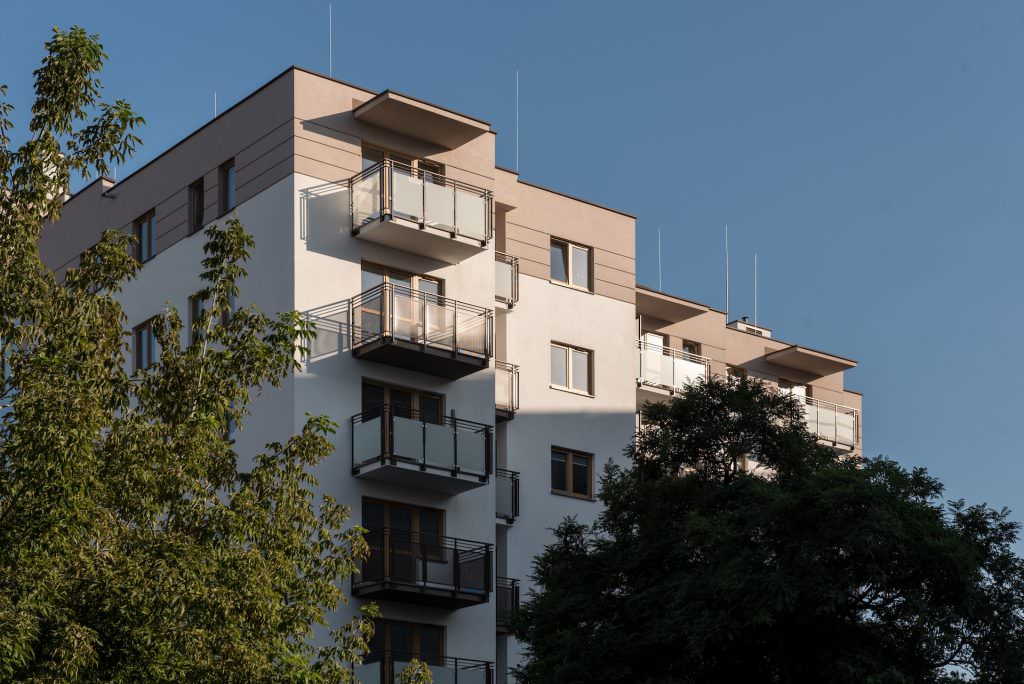 Budynek osiedla w Warszawie w wieczornym świetle, balkony i zieleń