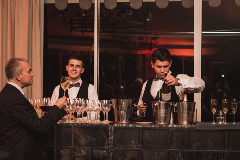 Bartenders at the very serve wine in glasses