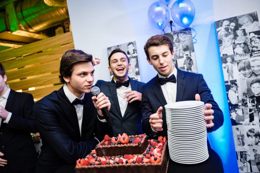The birthday boy speaks to the microphone, the second shouts something and the third holds a stack of plates