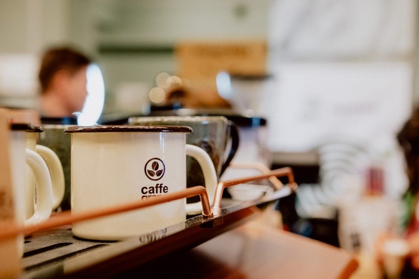 Więzienny kubek Caffe Grano stoi na ekspresie do kawy