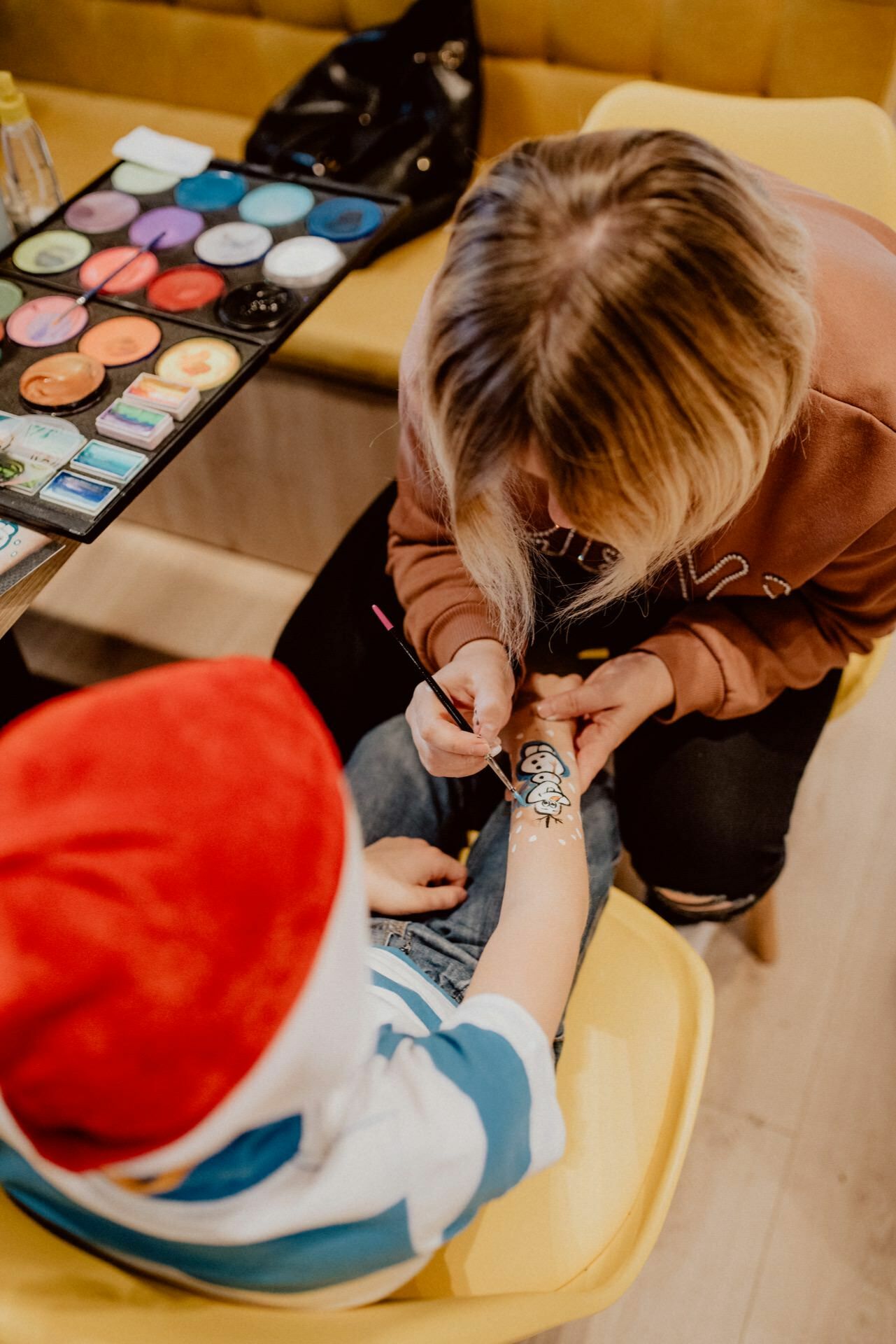 Animatorka maluje dziecku bałwana na ręce