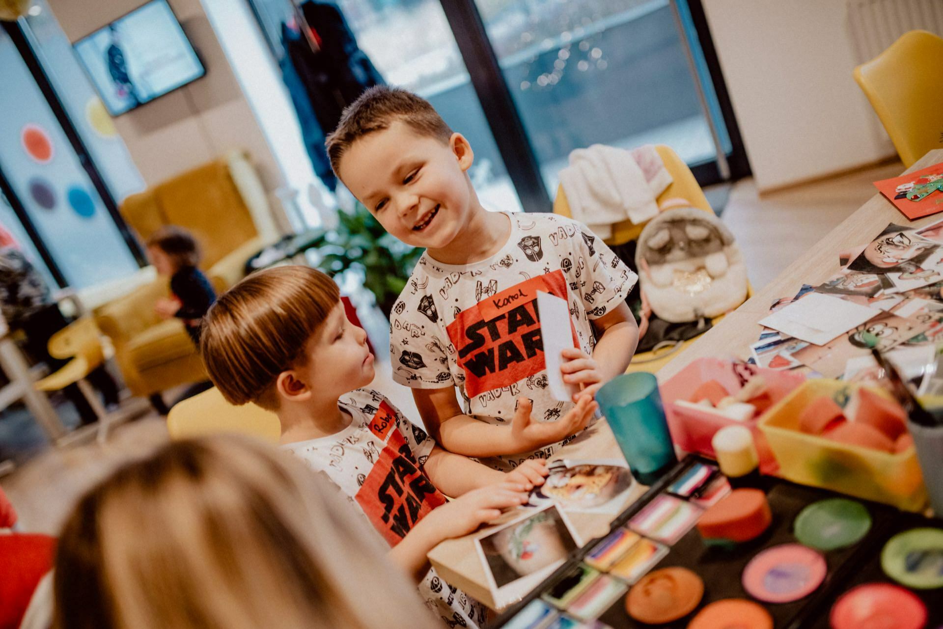 Dzieci w koszulkach STAR WARS rozmawiają przy stole do malowania twarzy