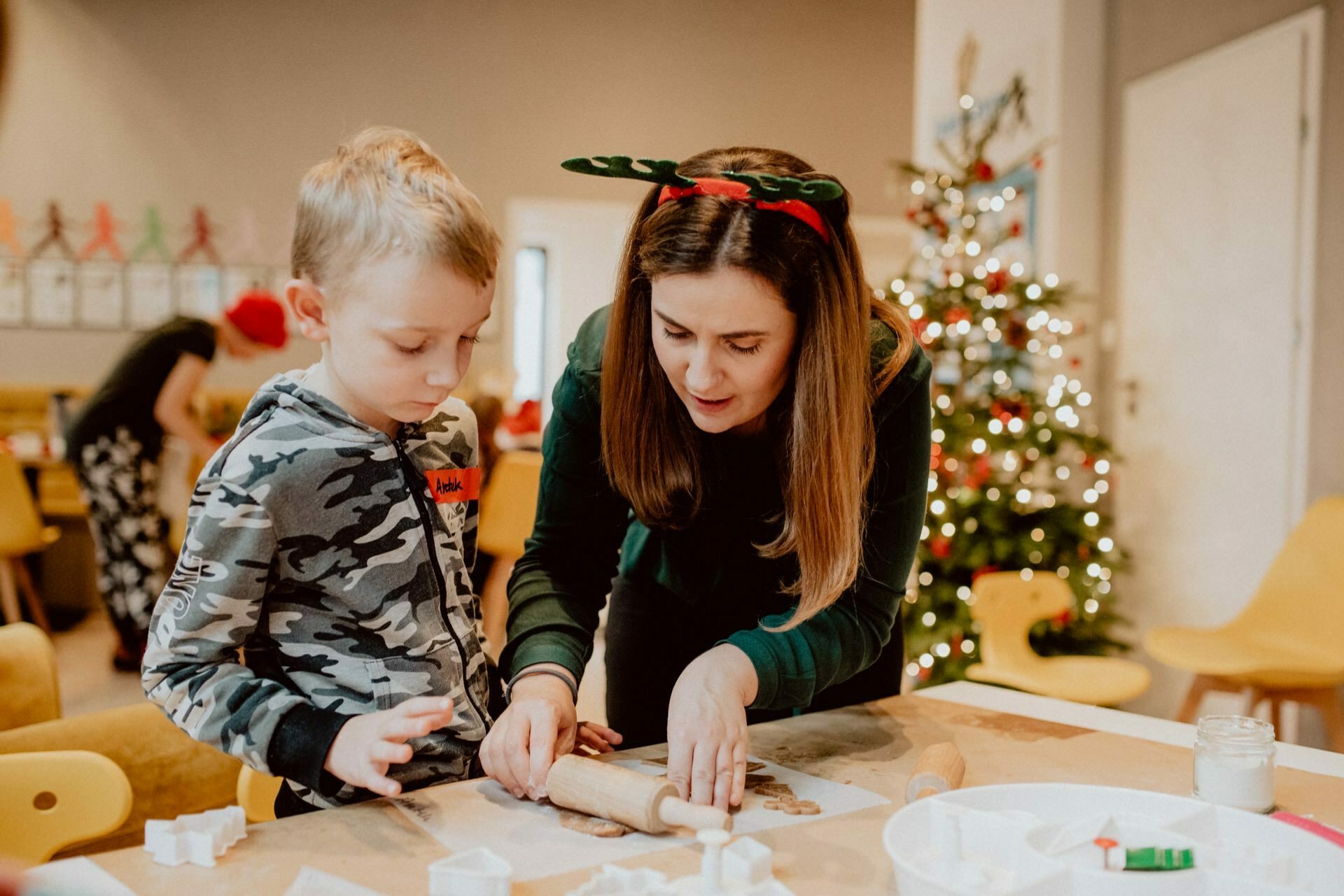 Teacher shows child how to roll Christmas gingerbread